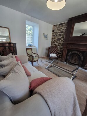 Ein Wohnzimmer mit einer Couch, Sesseln, einem Kamin und einer Steinwand.