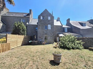 A stone house with a central tower, a wooden fence, and a potted plant in the yard. - Ty Coq • Authentic Breton home - 1650 (Plouescat)