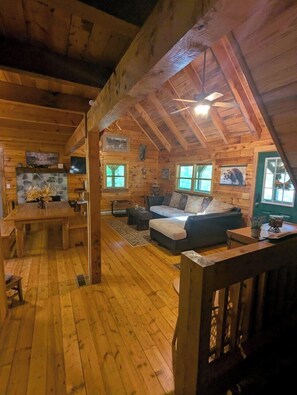 Una cabaña acogedora con interior de madera, comedor, sofá y chimenea.