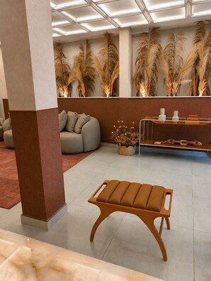 Um lobby moderno com um sofá, um banco de madeira e plantas decorativas.