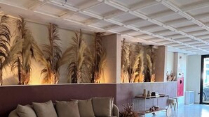 A modern lobby with a curved sofa, a large decorative wall, and a reception desk. - Missal Hotel (Aparecida)