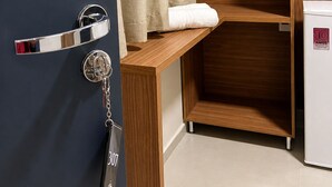 A hotel room with a wooden wardrobe, a minibar, and a door with a keychain. - Missal Hotel (Aparecida)