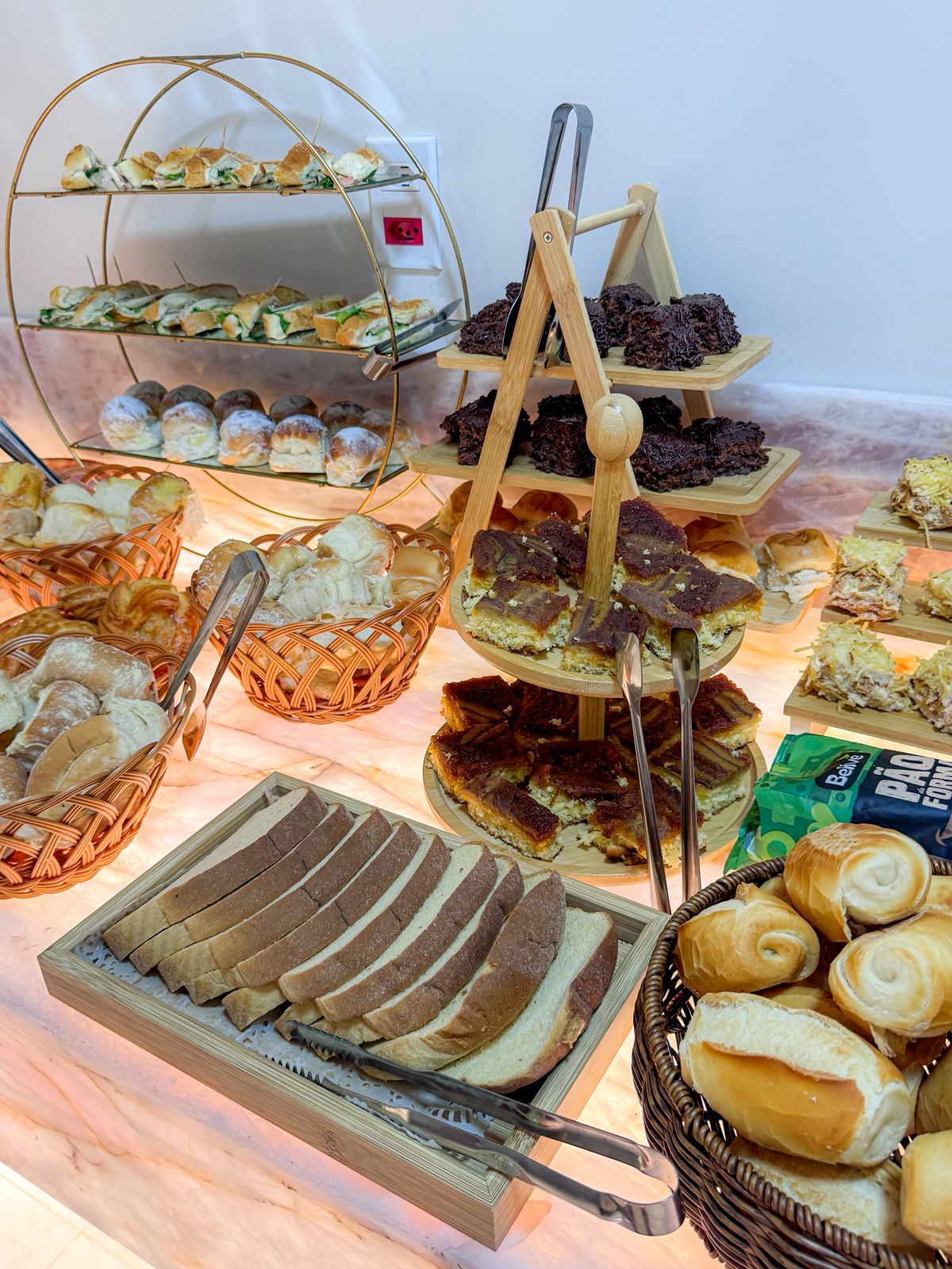 Un bufé con diversas opciones de comida, incluyendo pan, pasteles y postres.