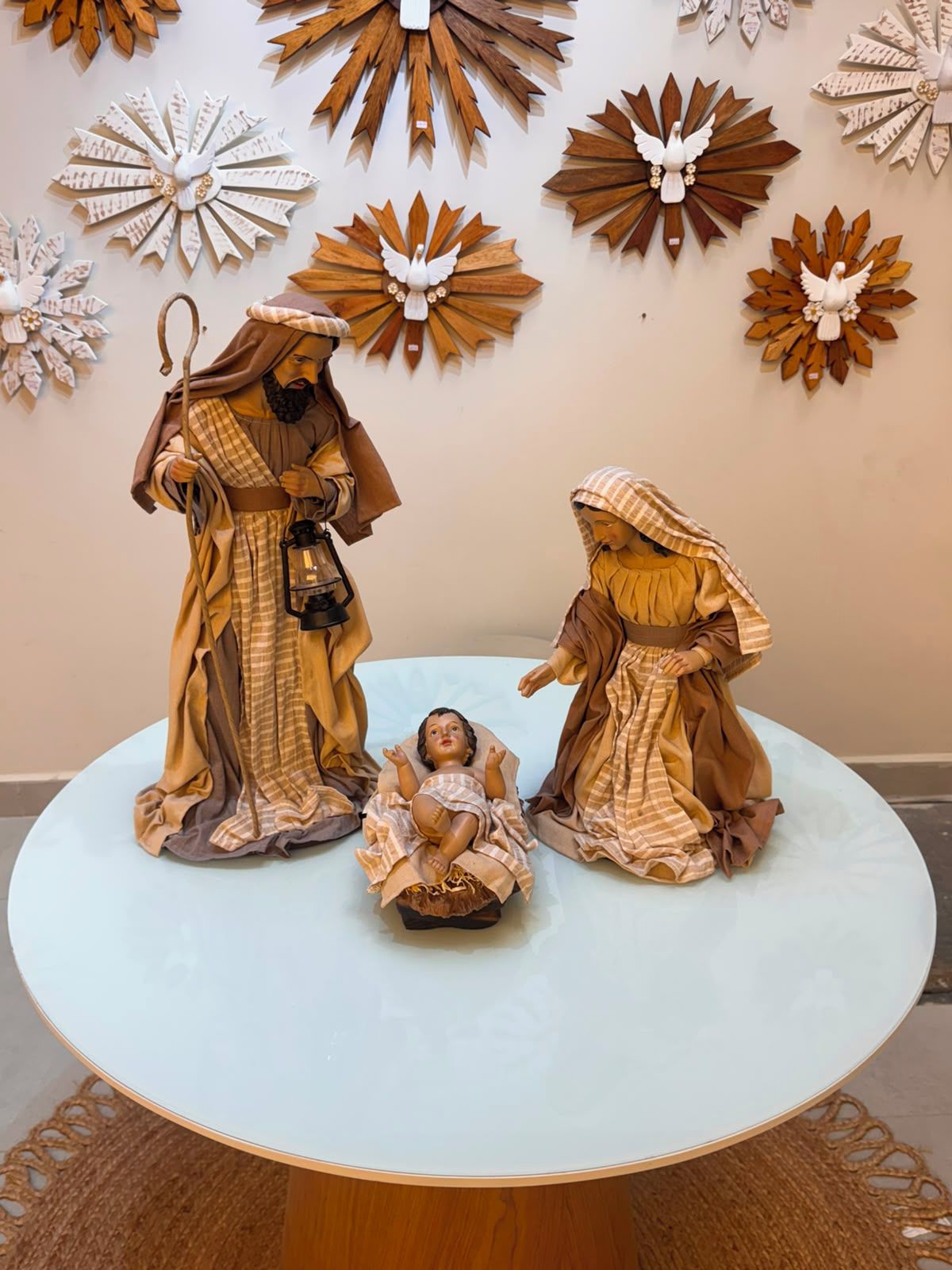 A nativity scene with three figures and a baby on a round table.
