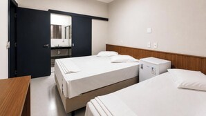 A hotel room with two beds, a small refrigerator, a wooden nightstand, and a mirror. - Missal Hotel (Aparecida)