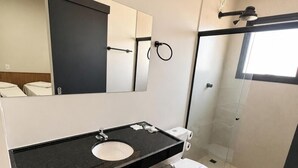 A modern bathroom with a black countertop sink, white toilet, and a glass shower enclosure. - Missal Hotel (Aparecida)