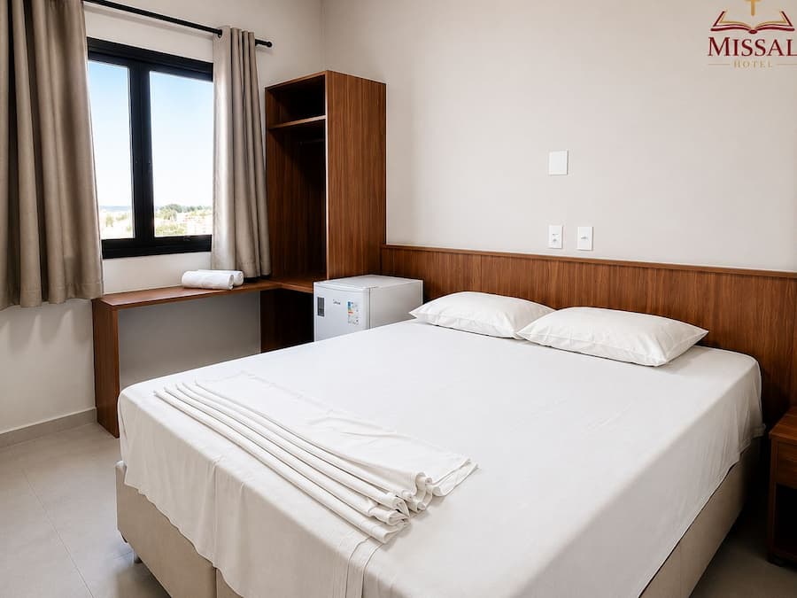 Una habitación de hotel con cama, escritorio, armario y ventana con cortinas.