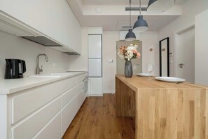 Eine moderne Küche mit weißen Schränken, einer Holzeinsel, einer Kaffeemaschine und einer Vase mit Blumen.