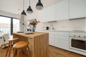 Eine moderne Küche mit einer Holztheke, Barhocker, Pendelleuchten und Blick auf die Stadt.