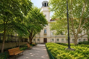 Ein Innenhof mit einem Weg, Bänken und einem Gebäude mit einem Turm.