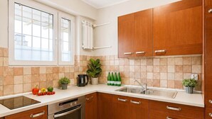 Eine moderne Küche mit Holzausstattung, einem Geschirrspüler, einem Backofen und einem Fenster mit Jalousien.