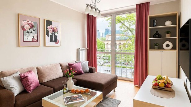 Ein modernes Wohnzimmer mit einem braunen Sofa, einem Glastisch und einer weißen TV-Konsole.