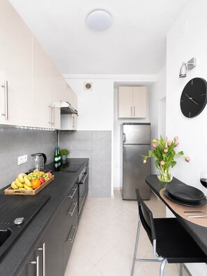 Eine moderne Küche mit schwarzem Arbeitsplatz, Edelstahlgeräten und einer Essecke mit einem schwarzen Stuhl und Tisch.