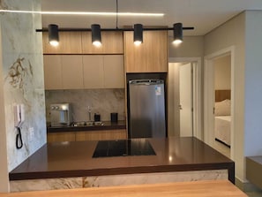 A modern kitchen with a marble countertop, stainless steel appliances, and pendant lighting.