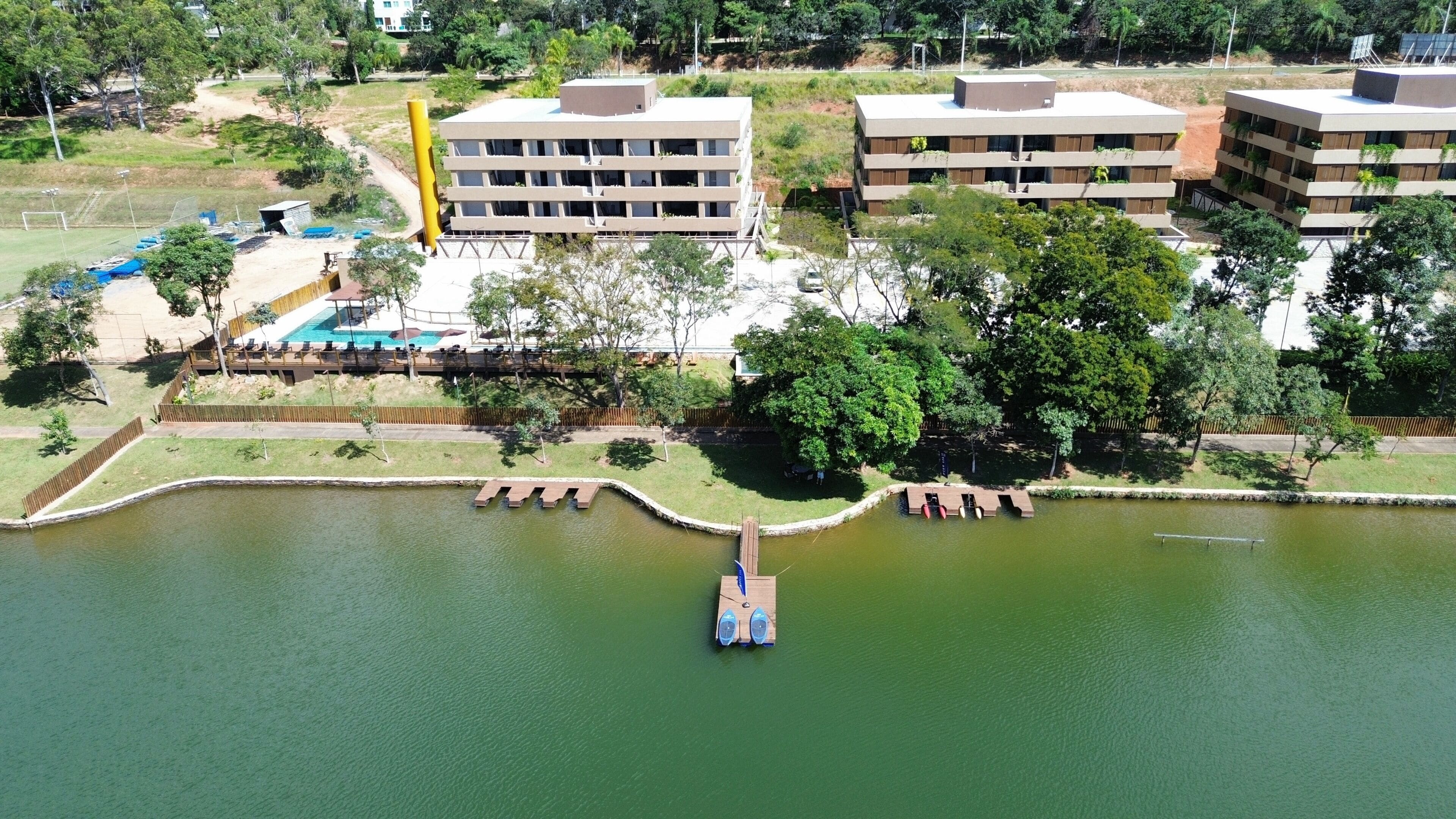 An aerial view of a lakeside property with a dock, buildings, and a swimming pool.
