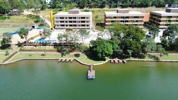 An aerial view of a lakeside property with a dock, buildings, and a swimming pool.