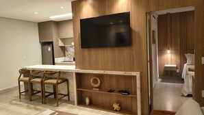 Una sala de estar moderna con un televisor montado en la pared, una mesa de centro de madera y un sofá.