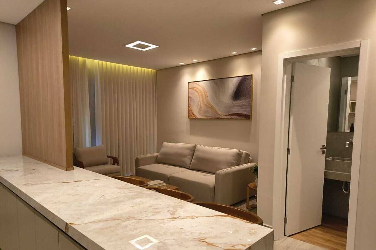 Una cocina moderna con encimera de mármol, sofá color crema y un cuadro en la pared.