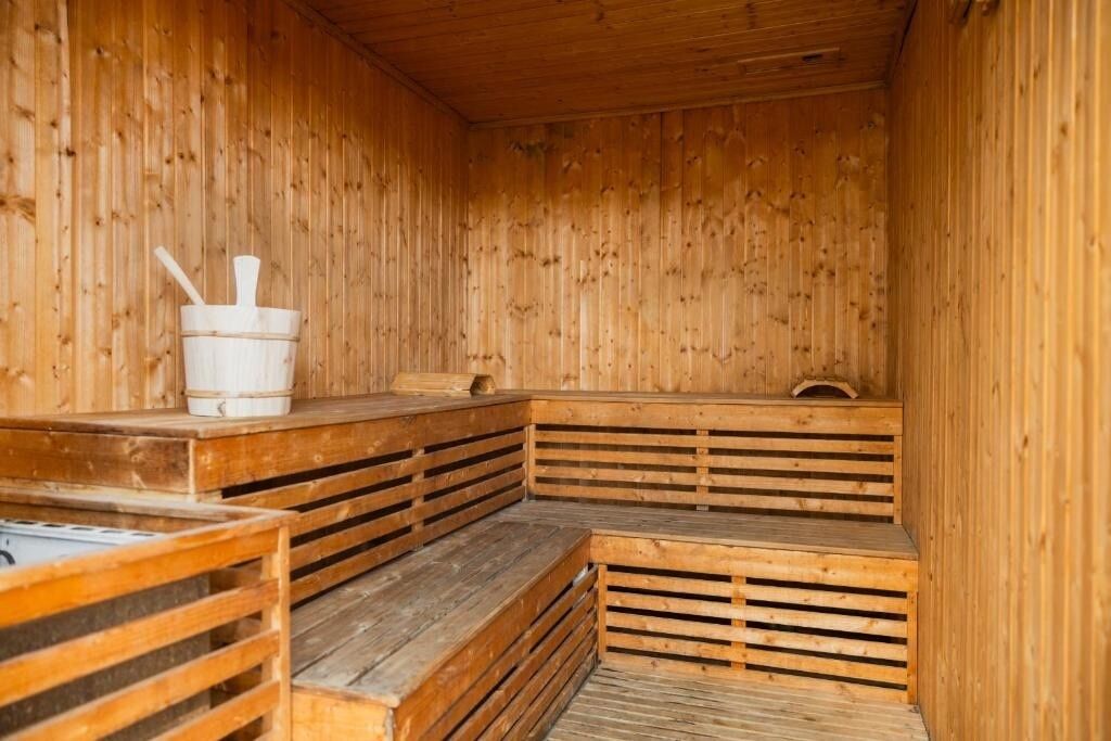 Una sauna con bancos de madera y un balde con una cuchara.