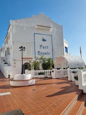 Ein weißes Gebäude mit einem Schild mit der Aufschrift 'Port Royale', einem mit Fliesen belegten Innenhof und einem weißen Laternenpfahl.