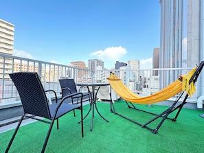 Une terrasse sur le toit, avec un hamac, des chaises et une table.