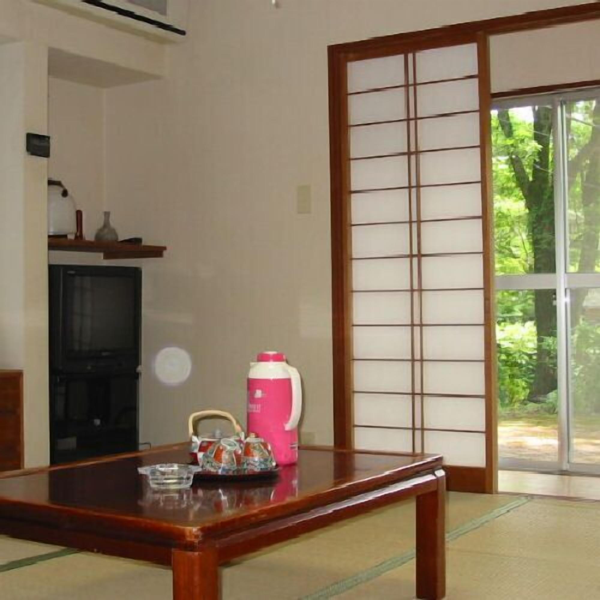 Ein traditioneller japanischer Raum mit Tatami-Böden, einer Schiebetür und einem Fernseher.