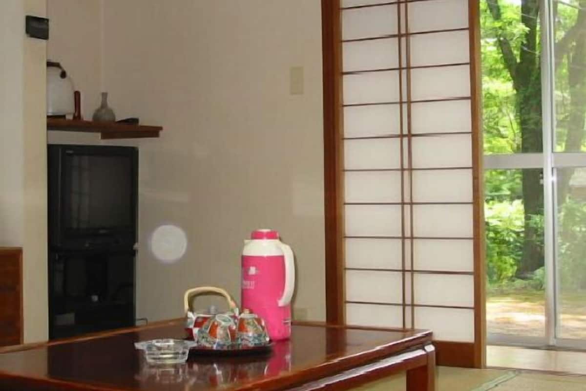 A traditional Japanese room with tatami flooring, a sliding door, and a television.