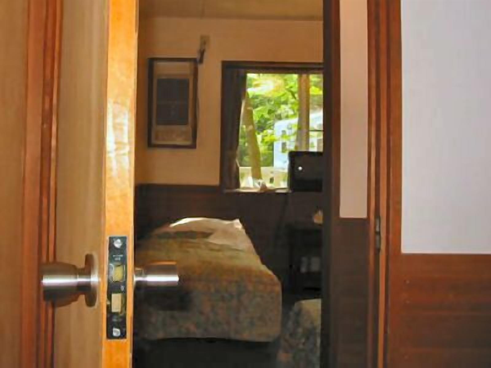 Ein Zimmer mit einem Bett, einem Fenster und einer Tür mit Bedienfeld.