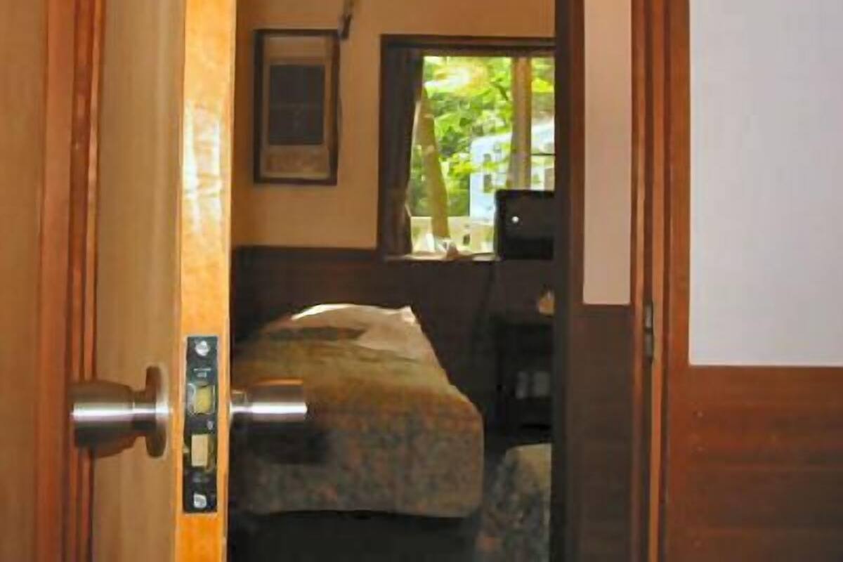 A room with a bed, a window, and a door with a control panel.