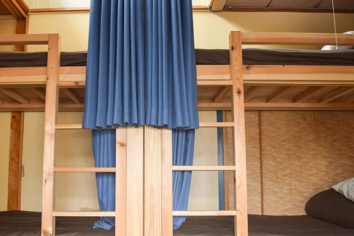 A bunk bed room with a curtain, wooden beams, and a patterned wall.