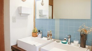A bathroom with two sinks, a mirror, and a blue-tiled wall.