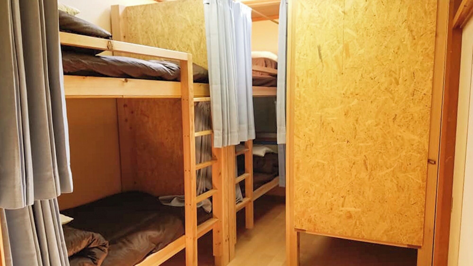 Huoneessa on kerrossänky, joka on tehty puusta. Alakuonossa on patja, ja huoneessa on myös pieni puinen kaappi.