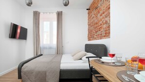 Een moderne kamer met een bed, een eettafel en een bakstenen muur.