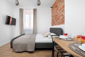 Ein modernes Zimmer mit einem Bett, einem Esstisch und einer Ziegelwand.