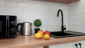 Eine Küche mit Mikrowelle, Wasserkocher, Spüle und Obst auf der Arbeitsfläche.