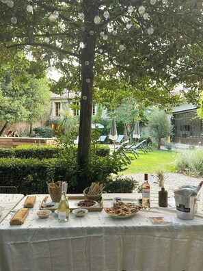An outdoor dining area with a table set for a meal, surrounded by greenery and a view of a courtyard. - Historic house in the heart of Provence (Brignoles)
