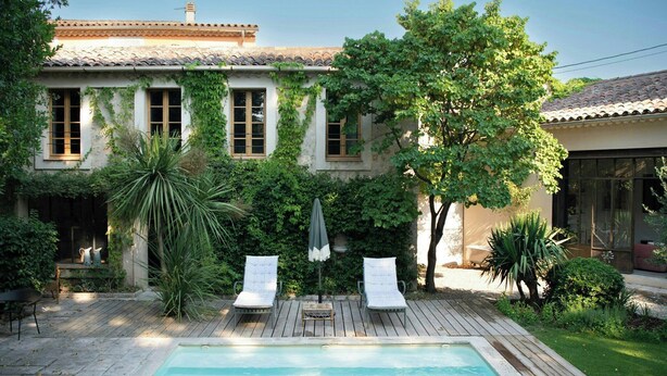 A pool with two lounge chairs, a wooden deck, and a building with ivy-covered walls. - Historic house in the heart of Provence (Brignoles)