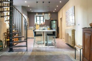 A modern kitchen with a central island, a spiral staircase, and pendant lighting. - Historic house in the heart of Provence (Brignoles)