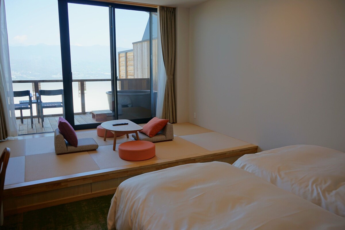 A hotel room with a balcony, a sofa, a small table, and two beds.