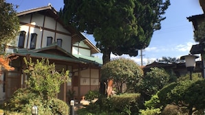 A traditional Japanese house with a wooden exterior, a sloped roof, and a garden with various plants and trees. - Nadaya Ryokan (Mimasaka)