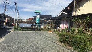 A traditional Japanese building with a signboard, a road in front, and some greenery. - Nadaya Ryokan (Mimasaka)