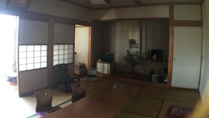 A traditional Japanese room with tatami flooring, a low wooden table, and sliding doors. - Nadaya Ryokan (Mimasaka)