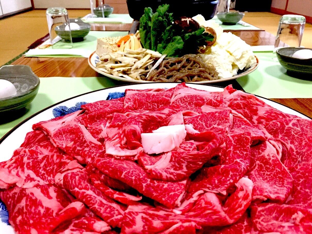 Ein Esstisch mit verschiedenen Speisen, darunter geschnittenes Fleisch und Gemüse.