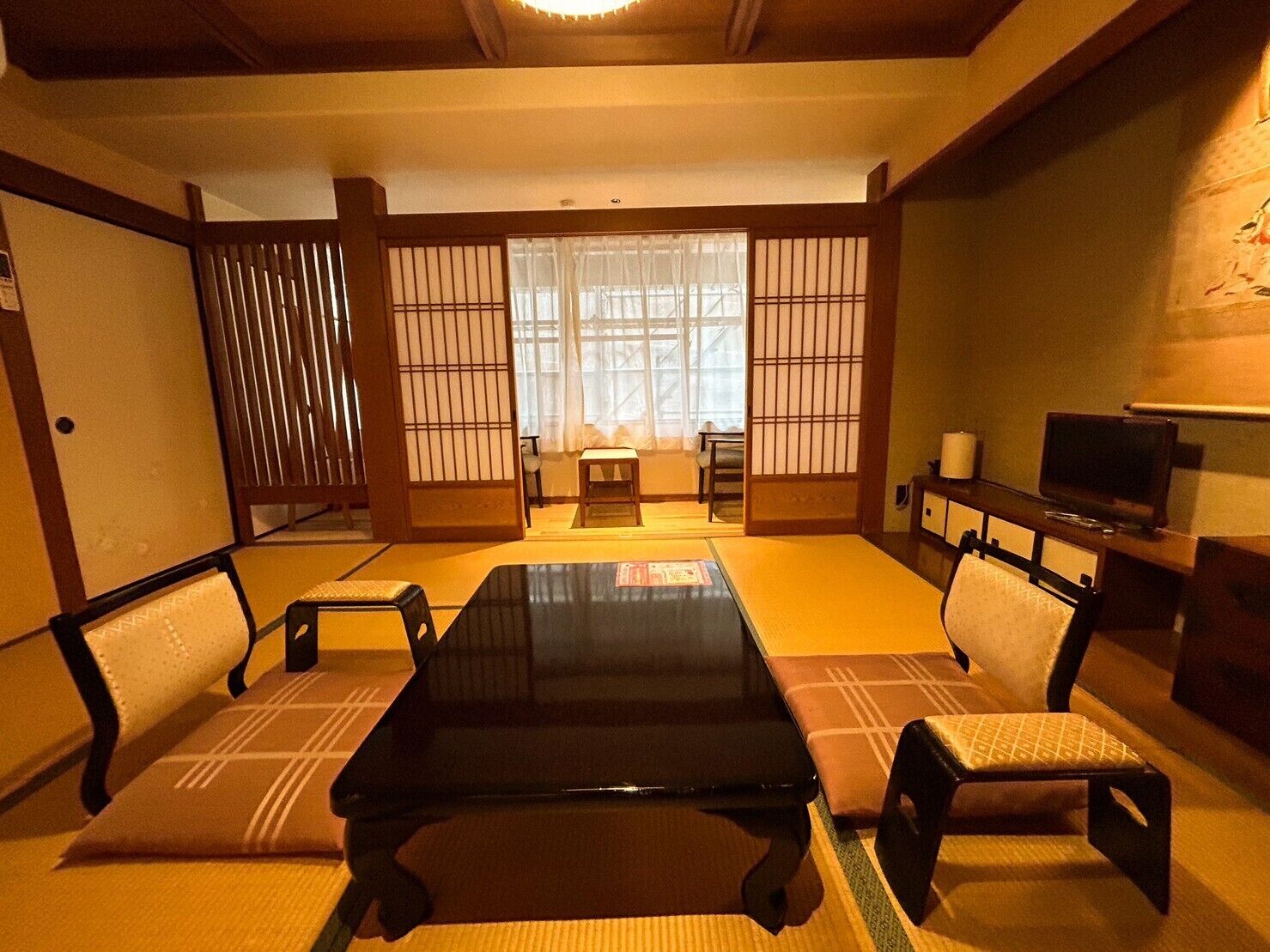 A traditional Japanese-style room with tatami flooring, a low table, and sliding doors.