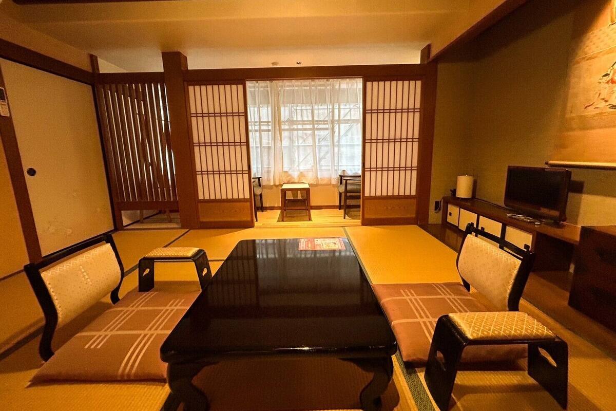 A traditional Japanese-style room with tatami flooring, a low table, and sliding doors.
