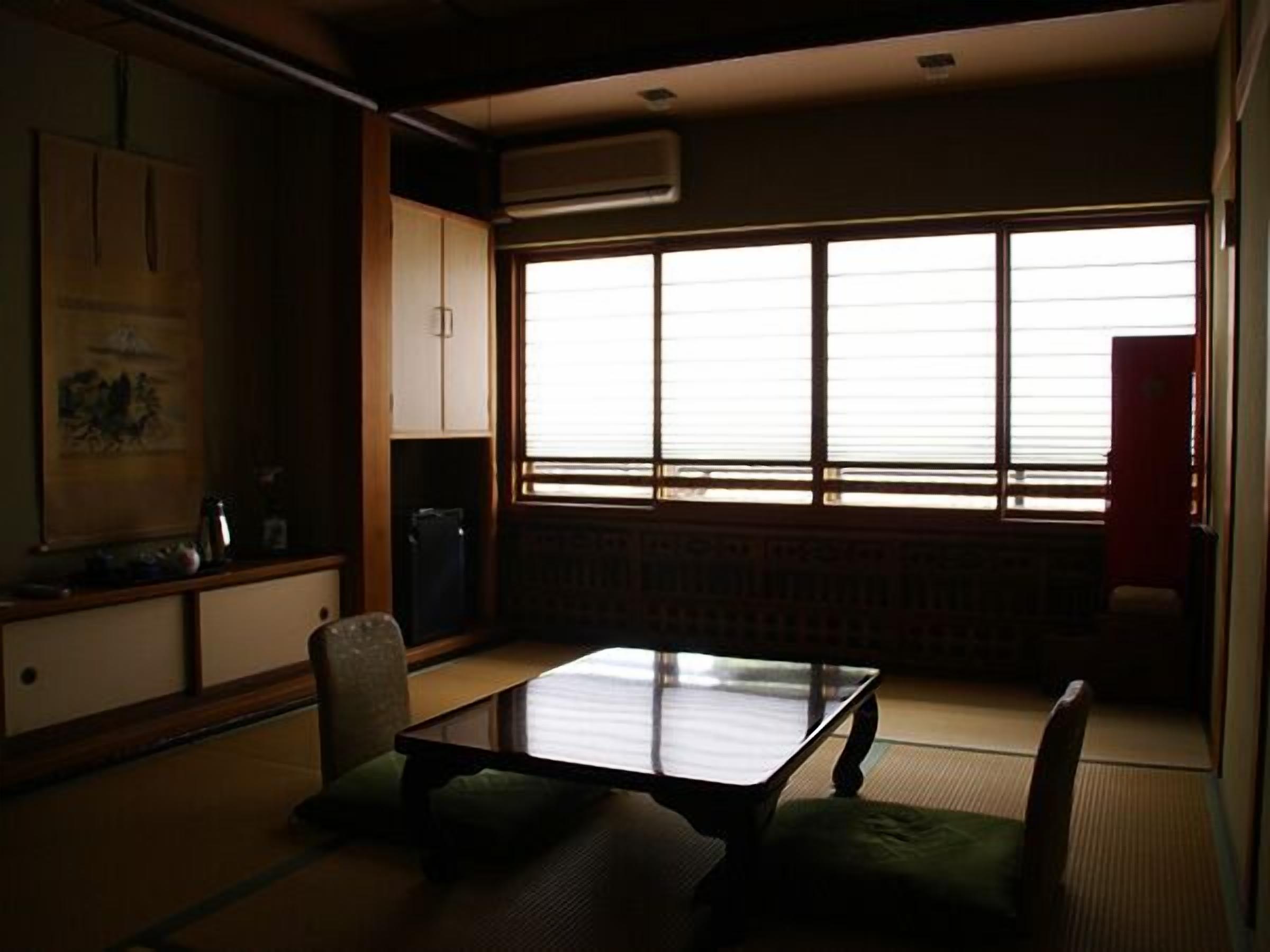 A traditional Japanese room with tatami flooring, a low table, and a sliding door.