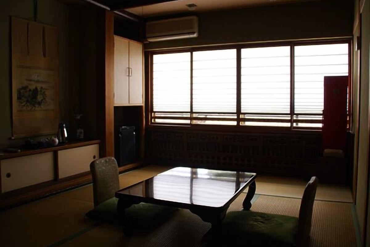 A traditional Japanese room with tatami flooring, a low table, and a sliding door.