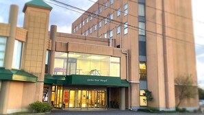 Un hotel con una entrada destacada, un toldo verde y un letrero que dice 'Garden Hotel Maryell'.
