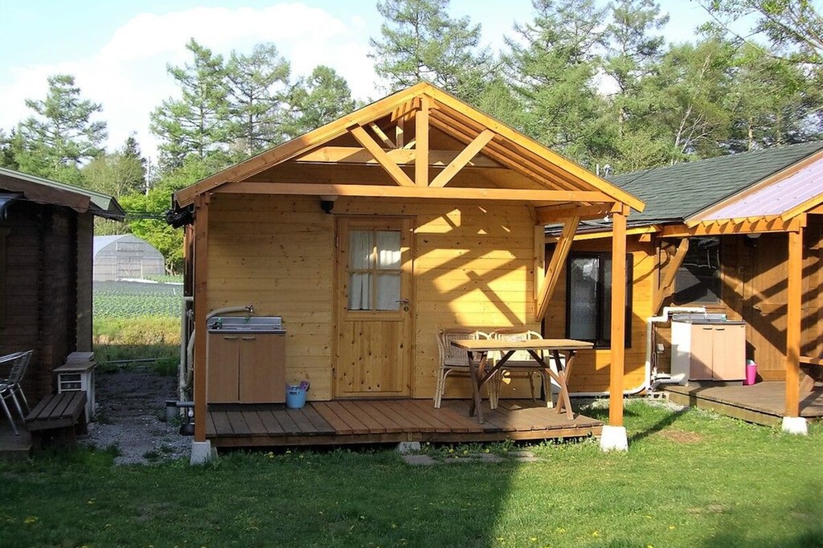 Una casetta di legno con veranda, un tavolino e una finestra.