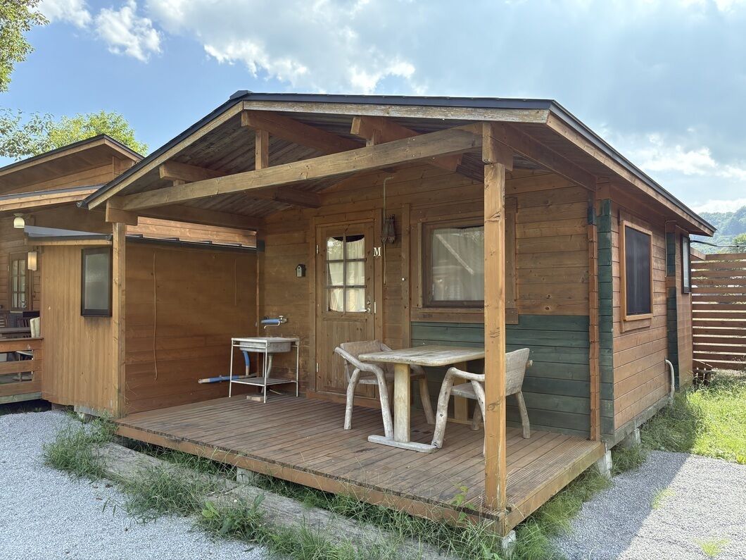Eine Holzhütte mit Veranda, einem Tisch und Stühlen.